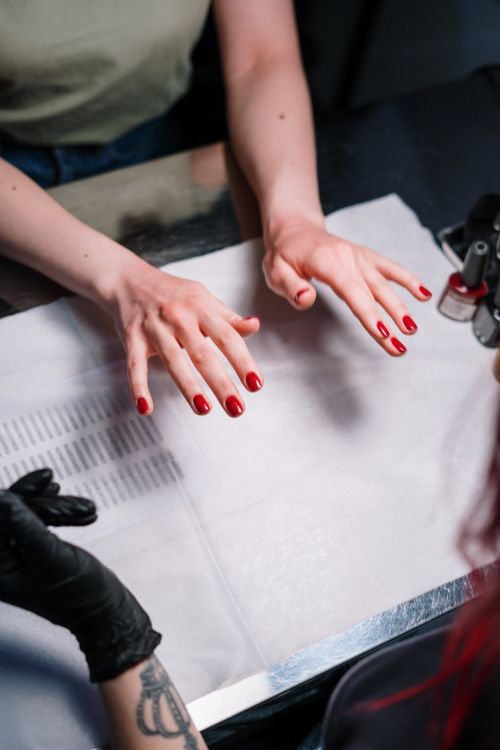 Dłonie z czerwonym manicure na stole stylistki